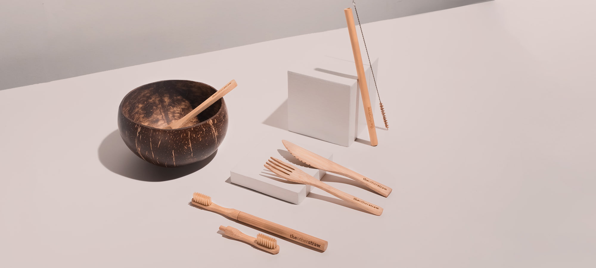 bamboo straw, bamboo cutlery, coconut bowl and bamboo toothbrush on table